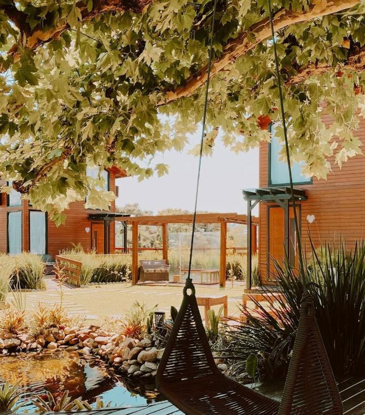Balanço debaixo da árvore, com o jardim e as cabanas