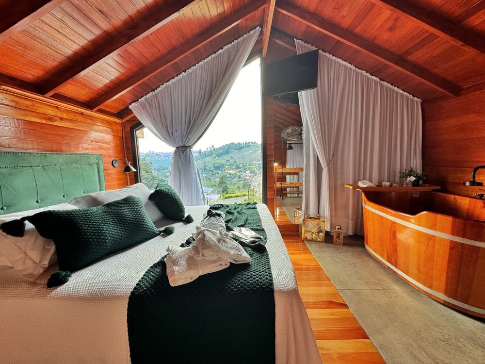 Quarto da Cabana Charmat com a cama e o ofurô de madeira