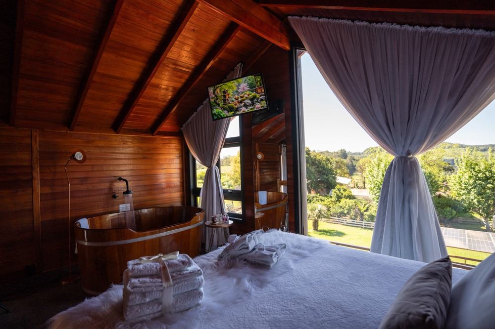 Ofurô de madeira ao lado da cama na Cabana Rosé