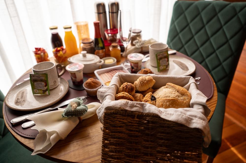 Cesta de pães, xícaras e geleias do café da manhã