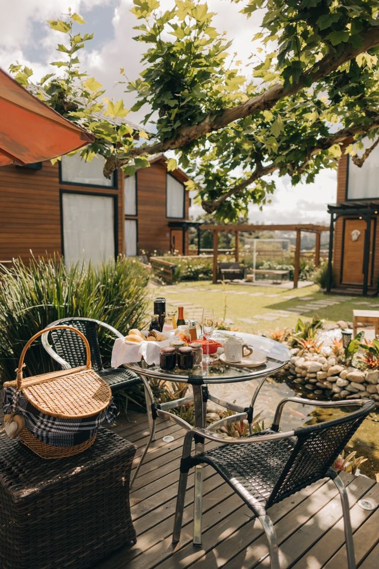 Café da manhã posto no deck, com a cesta de vime e o jardim