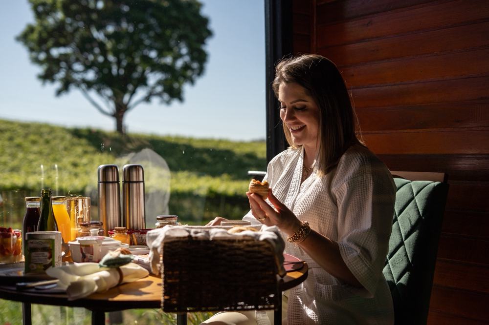 Café da manhã servido na mesinha da cabana, de frente pra janela com a árvore e o vinhedo